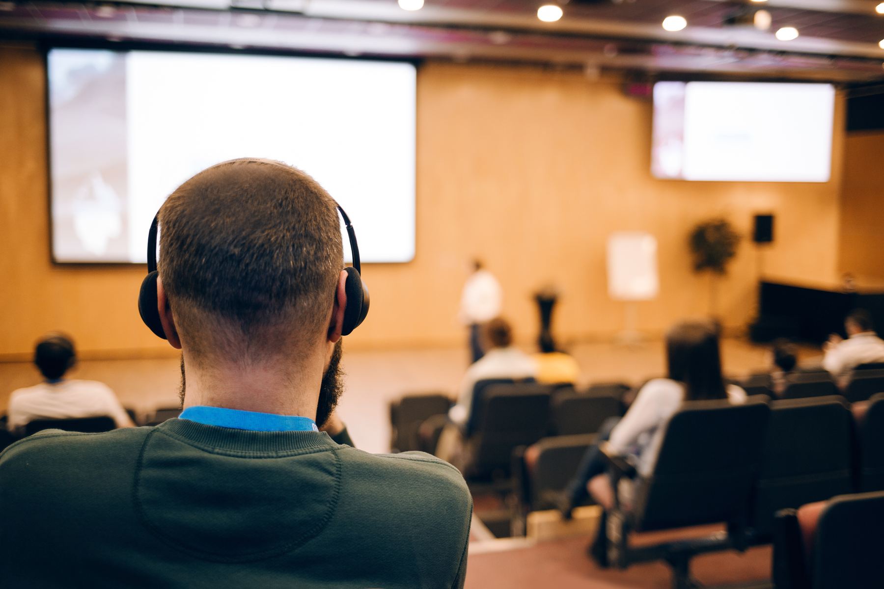 Intérprete con audífonos frente a una sala de conferencias